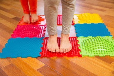 Çocuklar masaj paspasına basıyor. Düz taban ve hallux valgus önleme.