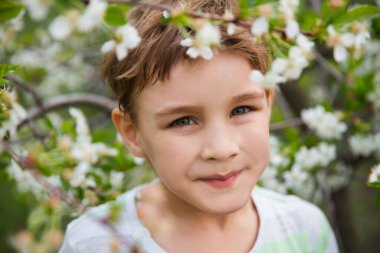 Çocuk dışarıda, güzel bir bahar bahçesinde. Çiçek bahçeli bir çocuk. Yaz zamanı.
