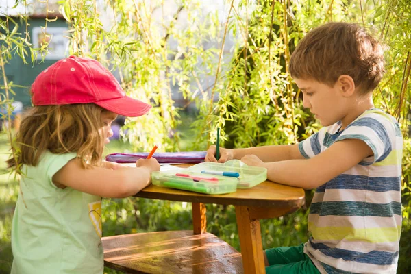 Homeschooling. Two children draw or do lessons in the garden near the house