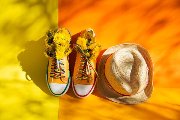 Yellow sneakers and straw hat on background with shadows of trees with copy space. End of quarantine. deep long shadows. Hello summer .