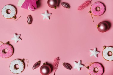 Noel süslemeleri topları, çörekler, hediyeler ve yıldızlar pastel renkli kağıt arka planlarına düşüyor. Düz yatış, üst manzara. Noel kartı gebeliği. Havalandırma kavramı