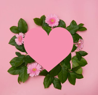 Çiçeklerle, yapraklarla ve pastel arka planda kağıt kalp pasteliyle yaratıcı bir düzen. tatil konsepti. Düz yerde, üst tarafta. Sevgililer Günü ile