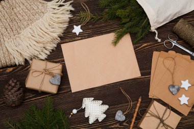 Sıfır atık, çevre dostu Noel, el yapımı hediyeler, doğal Noel süslemeleri, yün atkı, ahşap bir masada çam dalları. Düz yatış, üst görünüm, beyaz kağıt üzerinde yazı. El yapımı Noel hediyeleri