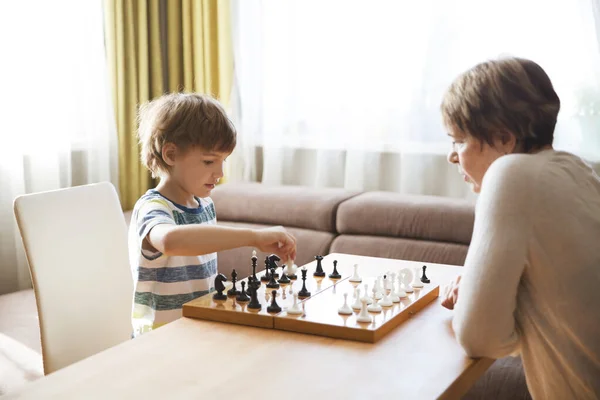 grandmom with grandson playing chess together at home. quarantine. health concept. Corona Virus. Quality Time. Family having fun playing at home. stay home concept