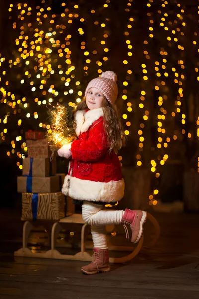 Kışlık elbiseli kız Noel arifesinde dışarıda hediye kutuları tutuyor..