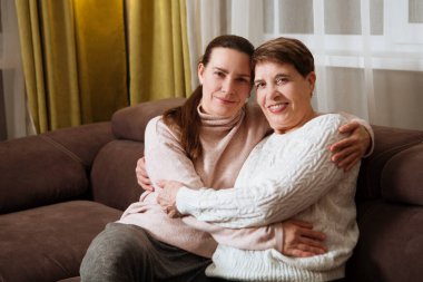 Mutlu yaşlı bayan anne ve yetişkin kız içeride sarılıyorlar. Aile zamanı. .
