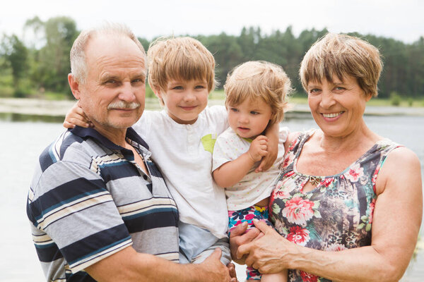 Happy Grandparents With Children On Walk in the summer outdoors