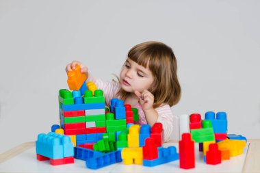 Bir sürü renkli plastik blok inşaatçısıyla oynayan bir çocuk.. 