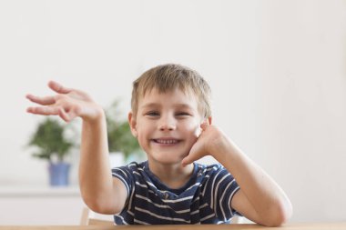 Gülümseyen okul çocuğunun portresi el sallıyor, kameraya bakıyor, video görüşmesi yapıyor veya evdeki webcam 'e video bloğu kaydediyor..