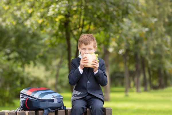 Schulkind Nimmt Seine Medizinische Maske Und Isst Draußen Ein Sandwich — Stockfoto