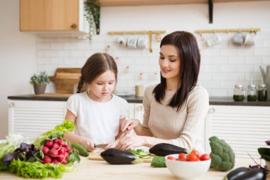 Anne ve kızı mutfakta birlikte sağlıklı sebzeler hazırlıyorlar. Çocuklara ebeveynlere yardım.