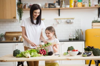 Anne ve kızı mutfakta birlikte sağlıklı sebzeler hazırlıyorlar. Çocuklara ebeveynlere yardım.