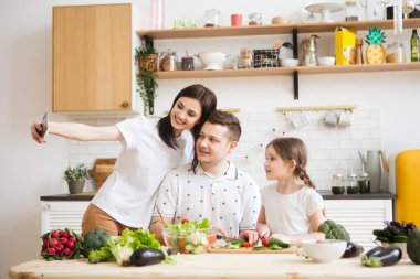 Mutlu aile annesi, baba ve kızı mutfakta birlikte sağlıklı sebzeler hazırlıyorlar.. 