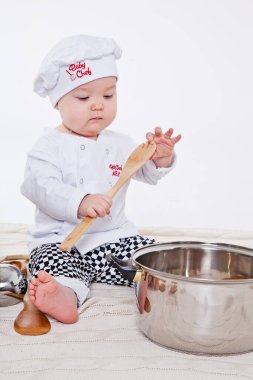 Aşçı kıyafetli küçük kız oyuncak yemek hazırlıyor.