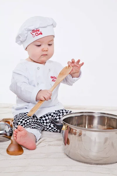 Aşçı kıyafetli küçük kız oyuncak yemek hazırlıyor.