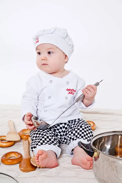 Aşçı kıyafetli küçük kız oyuncak yemek hazırlıyor.