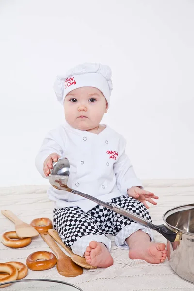 Aşçı kıyafetli küçük kız oyuncak yemek hazırlıyor.