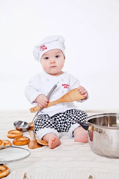 Aşçı kıyafetli küçük kız oyuncak yemek hazırlıyor.