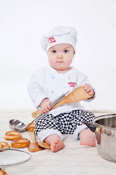 Aşçı kıyafetli küçük kız oyuncak yemek hazırlıyor.