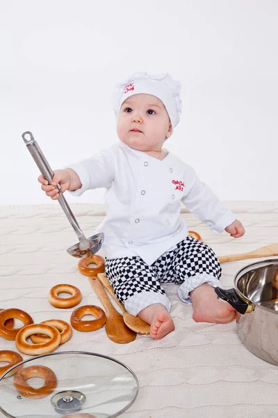 Aşçı kıyafetli küçük kız oyuncak yemek hazırlıyor.