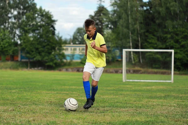 boy soccer player in a yellow t-shirt on the soccer field plays with a ball