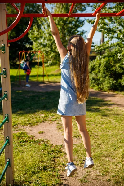 Beautiful girl hanging on the horizontal bar in the park — Stock Image Beautiful Girl Hanging Horizontal Bar Park Royalty Free Stock Images