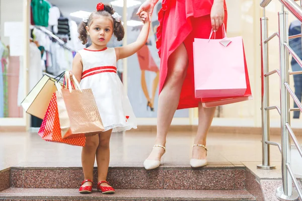 mom with little daughter in dresses at the mall with colored bags