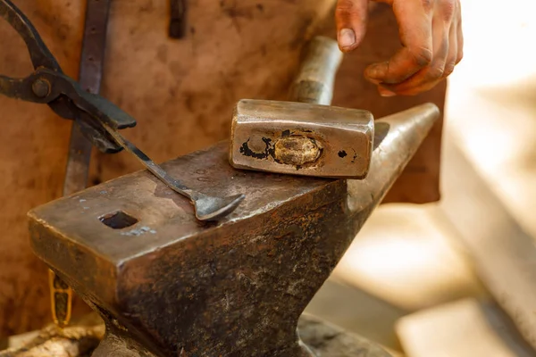 blacksmith makes a spoon on the anvil.