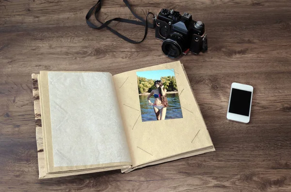 photo album, photo camera, phone on a wooden background, close-up