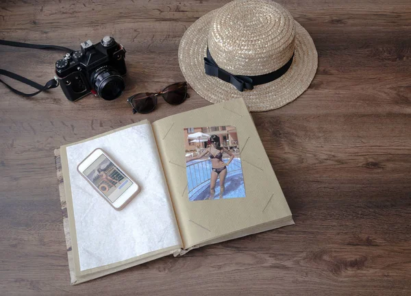 photo album, camera, phone, straw hat and sunglasses, on a wooden background