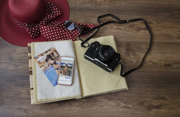 photo album, photo camera, phone and hat on a wooden background, close-up