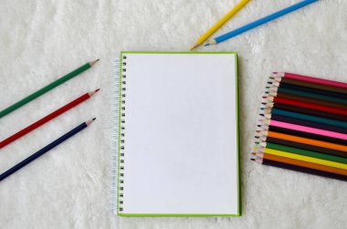 Defter ve hafif kabarık arka plan üzerine çizmek için renkli kalemler