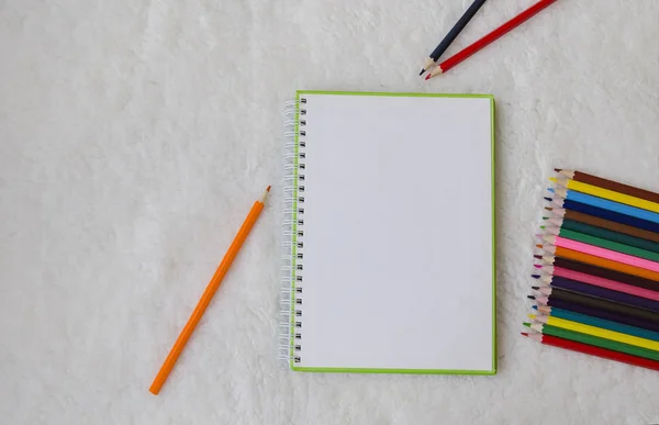 notebook and colored pencils for drawing on a light fluffy background