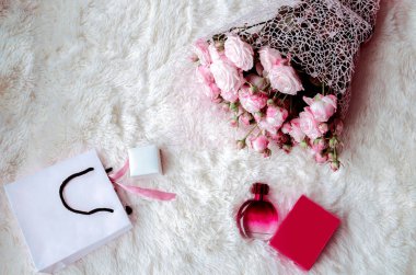 bir hediye, bir paket, bir parfüm ve kabarık beyaz bir arka plan üzerinde pembe gül buketi kutusu