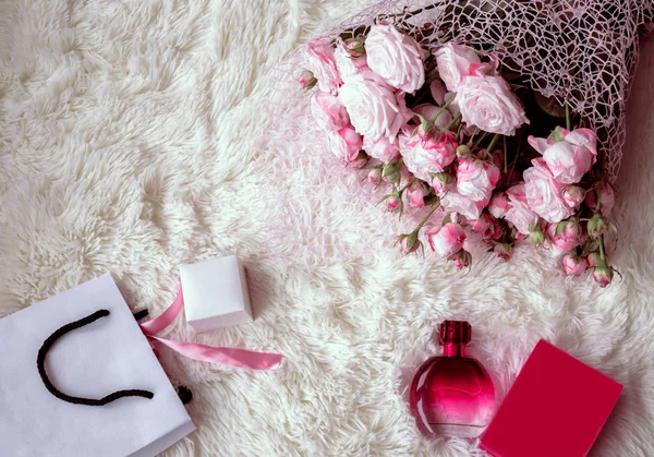 bir hediye, bir paket, bir parfüm ve kabarık beyaz bir arka plan üzerinde pembe gül buketi kutusu
