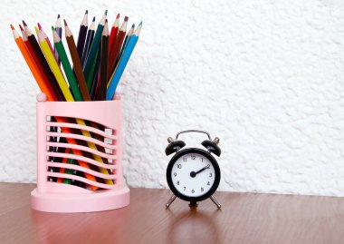 ahşap bir masa üzerinde oklar ve renkli kalemler ile siyah çalar saat