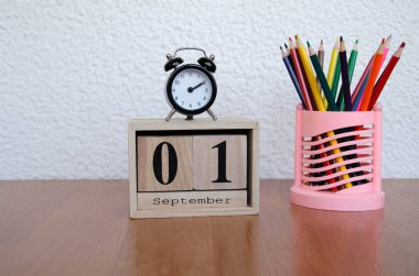 Eylül ilk tarihi ve bir çalar saat, masada renkli kalemler ile takvim