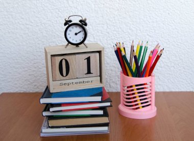 Eylül ilk tarihi ve bir çalar saat, masada renkli kalemler ile takvim