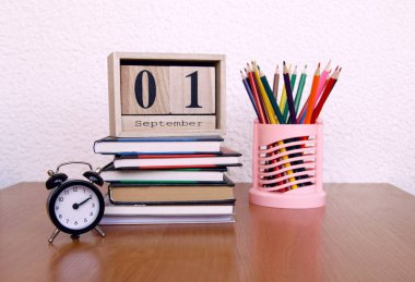 Eylül ilk tarihi ve bir çalar saat, masada renkli kalemler ile takvim