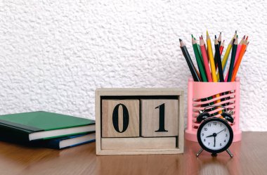 Tarihli ahşap takvim, çalar saat, masanın üzerindeki renkli kalemler, kitaplar, kapat