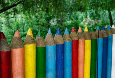 Renkli kalemler şeklinde eskrim, arka plandaki yeşil ağaçlara, parlak çitlere yakın çekime işaret ediyor.