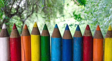 Renkli kalemler şeklinde eskrim, arka plandaki yeşil ağaçlara, parlak çitlere yakın çekime işaret ediyor.