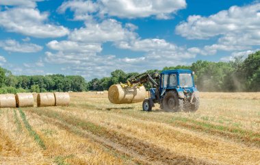 Yuvarlak balyalarda saman, tarlada traktör, yaz günü tarım işi.
