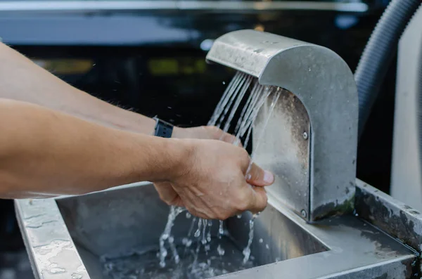 man washes his hands in a washbasin at a self-service car wash