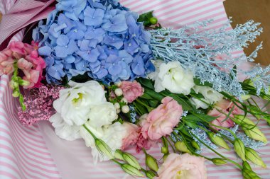 Östoma ve ortanca çiçekleri bir buketin içinde. Masadaki bayram hediyesi. Yakın plan.