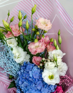 Östoma ve ortanca çiçekleri bir buketin içinde. Masadaki bayram hediyesi. Yakın plan.