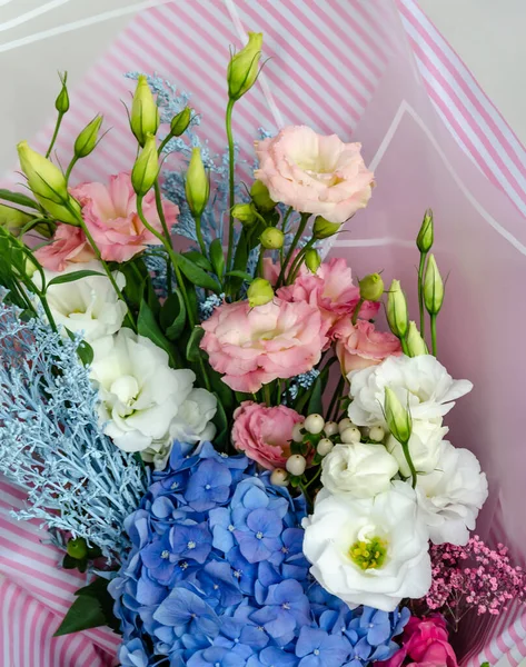 Östoma ve ortanca çiçekleri bir buketin içinde. Masadaki bayram hediyesi. Yakın plan.