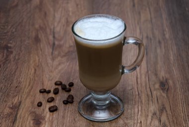 Sütlü kahve, latte, cappuccino, güzel bir cam bardakta sıcak içecek, ahşap bir masada.