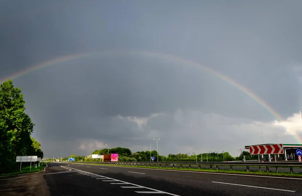 cloudy sky with rainbow, over motorway, cloudy summer day