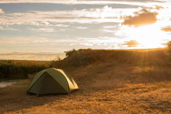 Yürüyüşçü günbatımı ve gündoğumu sırasında Nehri yakınında yeşil çadır